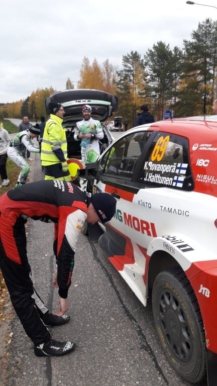 Kalle Rovanperän ja Jonne Halttusen punavalkoinen ralliauto numero 69 tien varressa, kuljettajat ja huoltajat auton ympärillä.